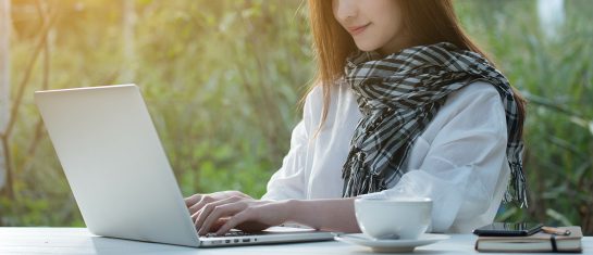 Beautiful young teenage woman freelance work with laptop with a cup of latte on sun light, freelance lifestyle conceptual