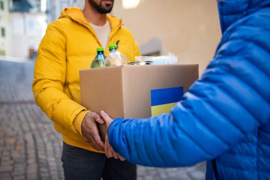 A cropped shot of volunteers collecting box with Humanitarian aid for Ukrainian refugees in street
