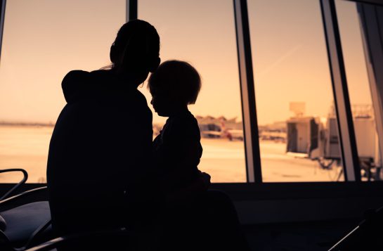 Single mother and child sitting at airport. Refugee immigrant co
